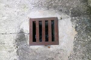 an iron gutter cover, with a rust color. Box shaped. on a concrete road photo