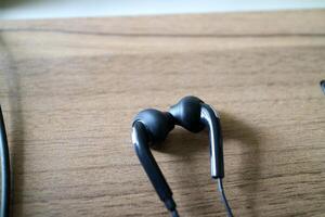 a pair of headsets with cables. black, placed on a table with a wooden motif photo