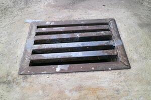 an iron gutter cover, with a rust color. Box shaped. on a concrete road photo