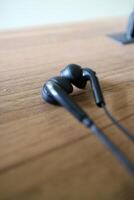 a pair of headsets with cables. black, placed on a table with a wooden motif photo