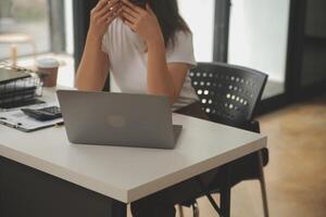 cansado negocio mujer soñoliento y aburrido desde sentado a un escritorio para un largo hora y tiene oficina síndrome foto