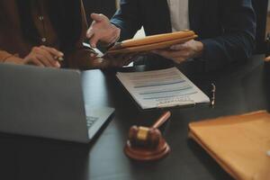 Justice and Law concept. Legal counsel presents to the client a signed contract with gavel and legal law or legal having team meeting at law firm in background photo