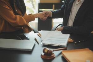 Justice and Law concept. Legal counsel presents to the client a signed contract with gavel and legal law or legal having team meeting at law firm in background photo