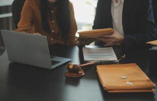 concepto de justicia y derecho. El asesor legal presenta al cliente un contrato firmado con mazo y derecho legal o una reunión de equipo legal en el bufete de abogados en segundo plano. foto