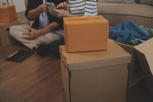 Two Asian blogger showing clothes in front of the camera to recording vlog live streaming at her shop. Online Shopping Cart notion. on sofa at home photo