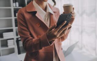 el retrato de una joven mujer asiática independiente está trabajando en su trabajo en una tableta de computadora en una oficina moderna. hacer un informe de análisis contable datos de inversión inmobiliaria, concepto de sistemas financieros y fiscales. foto