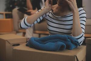 Two Asian blogger showing clothes in front of the camera to recording vlog live streaming at her shop. Online Shopping Cart notion. on sofa at home photo