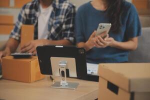 Two Asian blogger showing clothes in front of the camera to recording vlog live streaming at her shop. Online Shopping Cart notion. on sofa at home photo