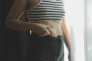 mujer cuerpo grasa barriga. obeso mujer mano participación excesivo barriga gordo. dieta estilo de vida concepto a reducir barriga y forma arriba sano estómago músculo. foto