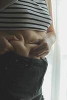 Women body fat belly. Obese woman hand holding excessive belly fat. diet lifestyle concept to reduce belly and shape up healthy stomach muscle. photo