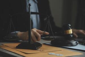 Business and lawyers discussing contract papers with brass scale on desk in office. Law, legal services, advice, justice and law concept picture with film grain effect photo