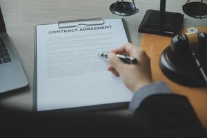 Business and lawyers discussing contract papers with brass scale on desk in office. Law, legal services, advice, justice and law concept picture with film grain effect photo