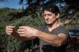 A Caucasian man adopts the Tree Hugging Posture during his Qi Gong training session. Rooted in ancient Chinese practices, this posture cultivates internal strength, balance, and energetic alignment. photo