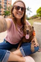 A happy woman with a tattooed arm takes a photo with her pet.