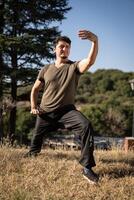 Caucasian middle-aged man practicing Tai Chi Chuan outdoors. photo