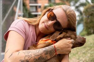 A woman with a tattooed arm lovingly embraces her pet. photo