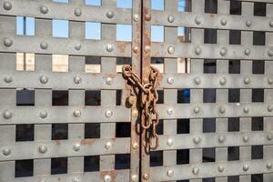 grey iron gate closed with rusty chain and padlock photo