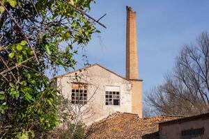 Old abandoned gray paper mill with a brick chimney pipe photo