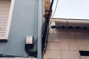 Exterior of a building with many electrical wires outside connected in a steel box on the wall photo