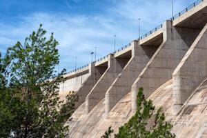 Side and bottom view of a dry concrete river dam with trees next to it photo