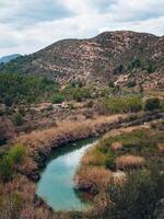 vertical landscape of a river flowing in a mountainous area on a cloudy day photo