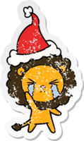 hand drawn distressed sticker cartoon of a crying lion wearing santa hat png