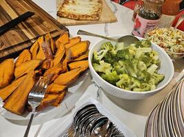 boiled broccoli and grilled sweet potato and orzo pasta salad served as appetizers for guests in a party photo