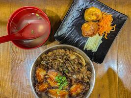 Japanese food called Buta Don or Gyu Don or Beef Rice Bowl or Pork Rice Bowl served with miso soup and fried egg roll. photo