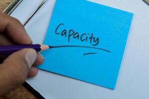 Concept of Capacity write on sticky notes isolated on Wooden Table. photo