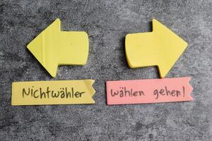 Concept of Nichtwahler und wahlen gehen write on sticky notes isolated on Wooden Table. photo