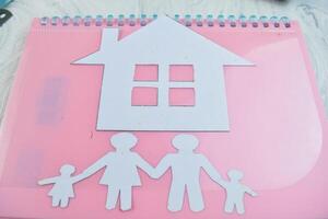 House Made of paperwork with family figures on wooden background metaphor for dream of home ownership photo