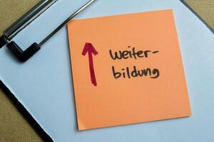 Concept of Weiter Bildung write on sticky notes isolated on Wooden Table. photo