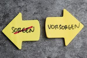 Concept of Sorgen un Vorsorgen write on sticky notes isolated on Wooden Table. photo