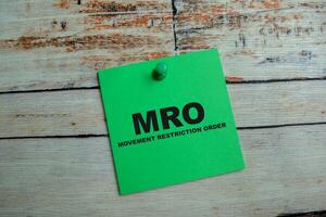 Concept of MRO - Movement Restriction Order write on sticky notes isolated on Wooden Table. photo