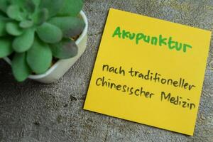 concepto de aprendizaje idioma - alemán. akupunktur eso medio acupuntura escrito en pegajoso notas alemán idioma aislado en de madera mesa. foto