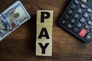 Concept of The wooden Cubes with the word Pay on wooden background. photo