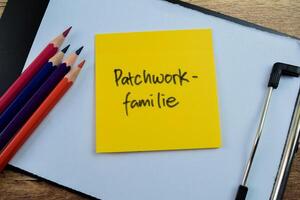 Concept of Patchwork Familie in Language Germany write on sticky notes isolated on Wooden Table. photo