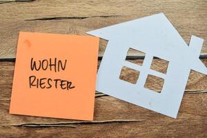 Concept of Wohn Riester in Language Germany write on sticky notes isolated on Wooden Table. photo