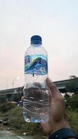 Close-up of hand holding mineral plastic Bottle with condensation. Bekasi, Indonesia, April 22, 2024 photo