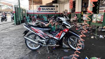 mechanic in overalls making diagnostics of motorbike near toolbox in workshop. Bekasi, Indonesia, April 22, 2024 photo