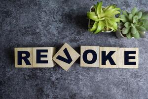 Concept of The wooden Cubes with the word Revoke on wooden background. photo