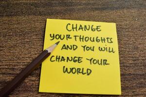 Concept of Change Your Thoughts and You Will Change Your World write on sticky notes isolated on Wooden Table. photo