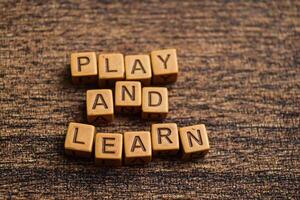 Concept of Play and Learn message written on wooden blocks. Cross processed image on Wooden Background photo