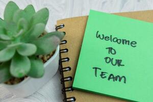 Concept of Welcome to our Team write on sticky notes isolated on Wooden Table. photo