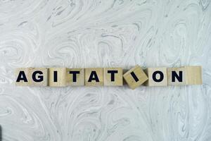 Concept of The wooden Cubes with the word Agitation on wooden background. photo