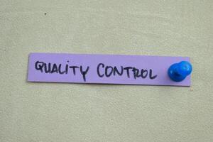 Concept of Quality Control write on sticky notes isolated on Wooden Table. photo