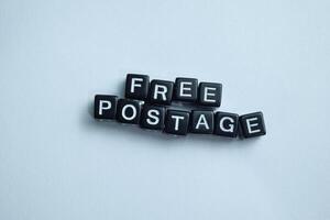 Concept of Free Postage written on wooden blocks. Cross processed image on Wooden Background photo