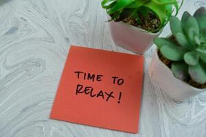 Concept of Time To Relax write on sticky notes isolated on Wooden Table. photo