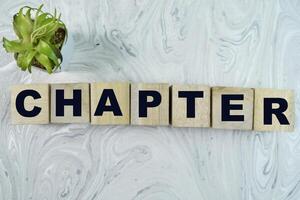 Concept of The wooden Cubes with the word Chapter on wooden background. photo