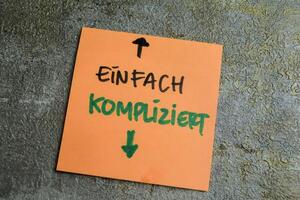 Concept of Learning language - German. Einfach Kompliziert it means Simply complicated written on sticky notes. German language isolated on Wooden Table. photo